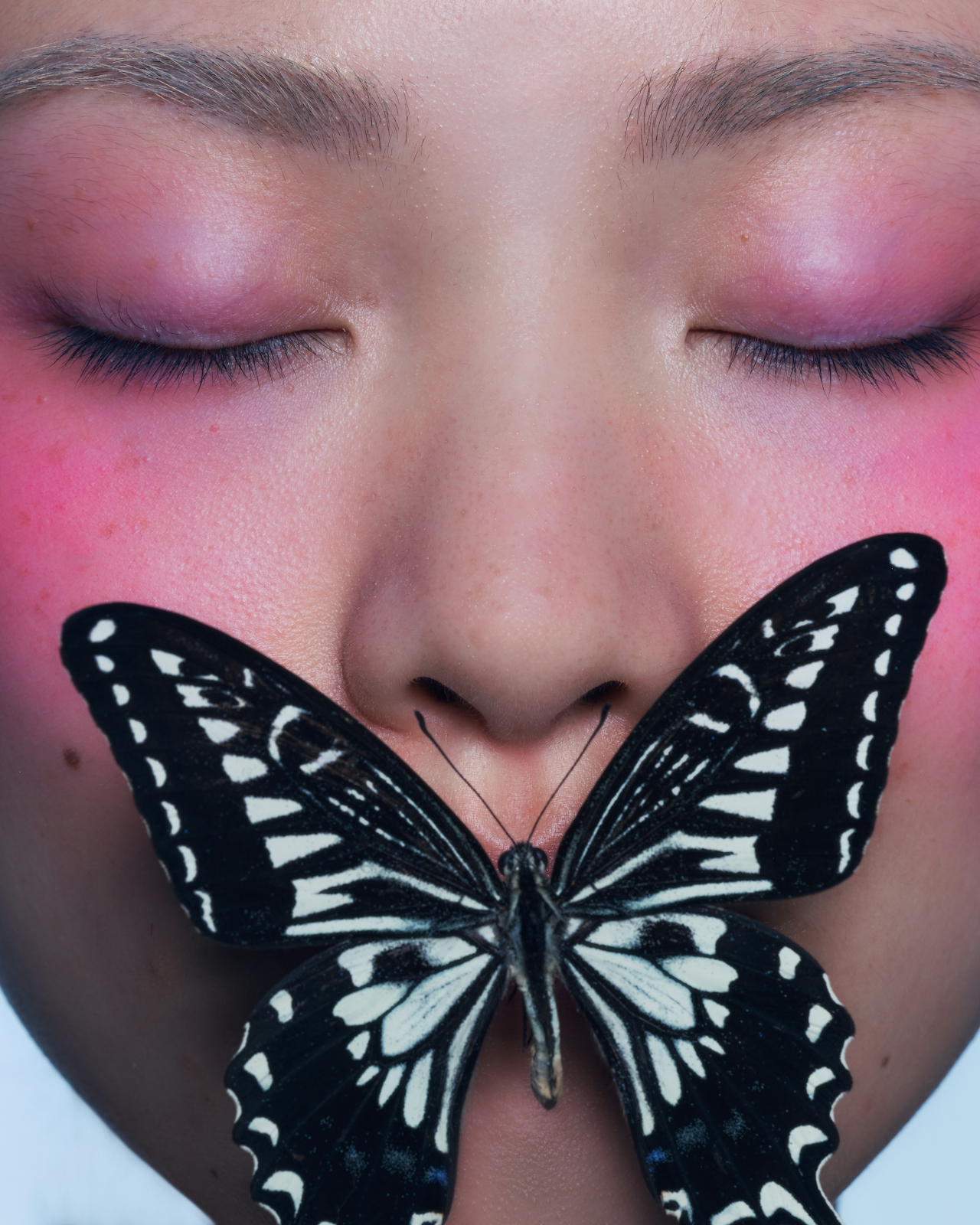 Retrato editorial con mariposa sobre el rostro — cuidado y detalle